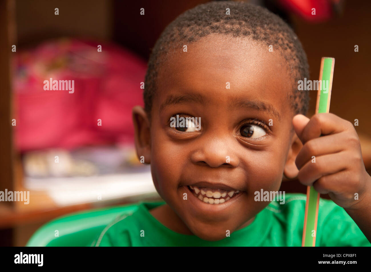 Child holding a pencil crayon, smiling Stock Photo