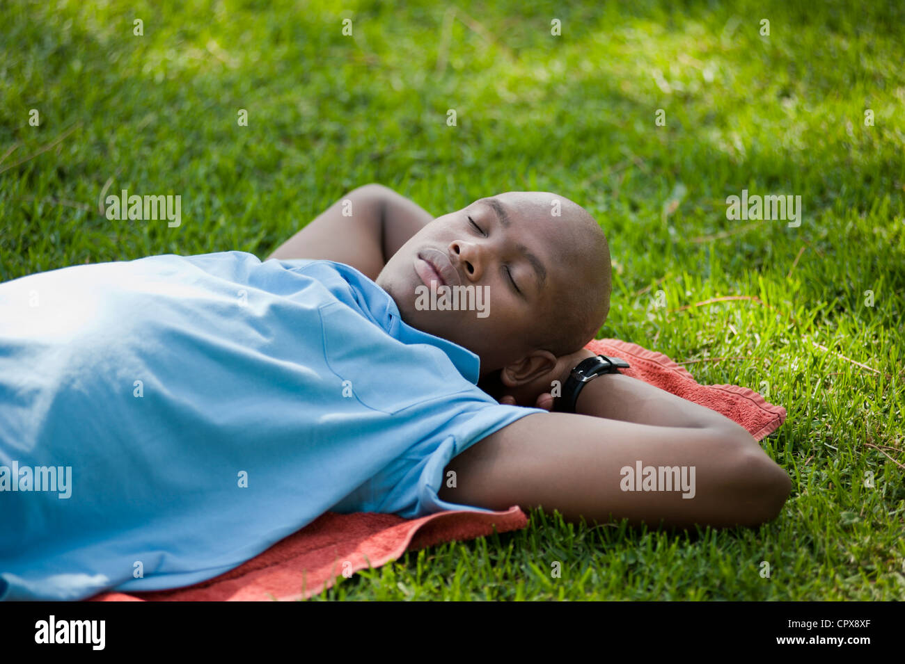 A young African man sleeping on the grass in a park Stock Photo