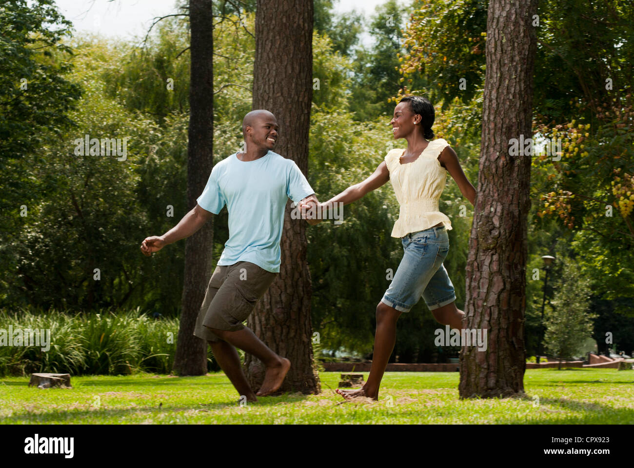 Young African couple running together through a park Stock Photo - Alamy