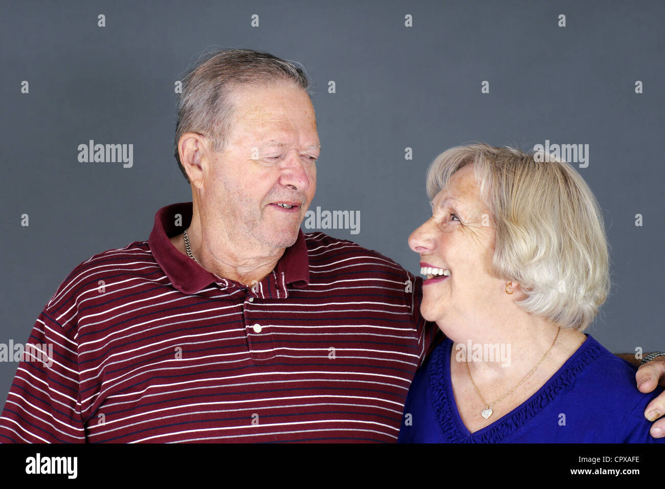 Happy senior couple laughing together, studio shot over grey background. Stock Photo