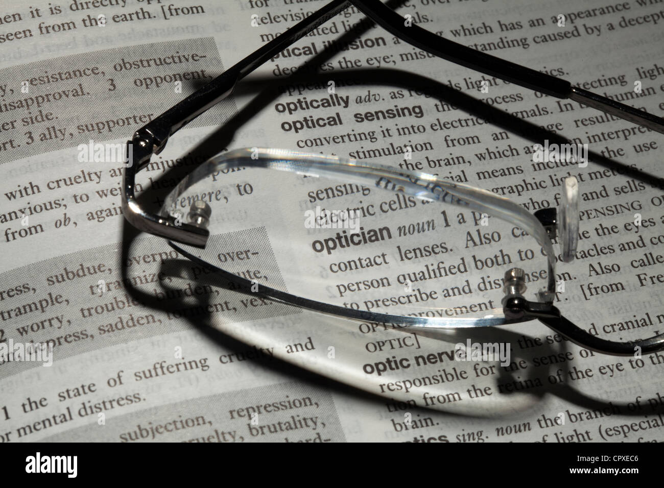 Reading glasses resting on book focusing on word optician Stock Photo