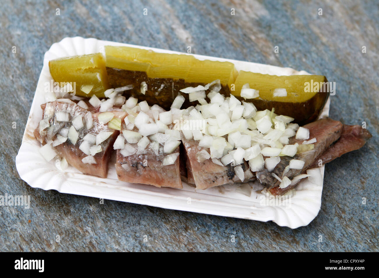 A traditional Dutch delicacy of raw herring with chopped onions and pickles Stock Photo