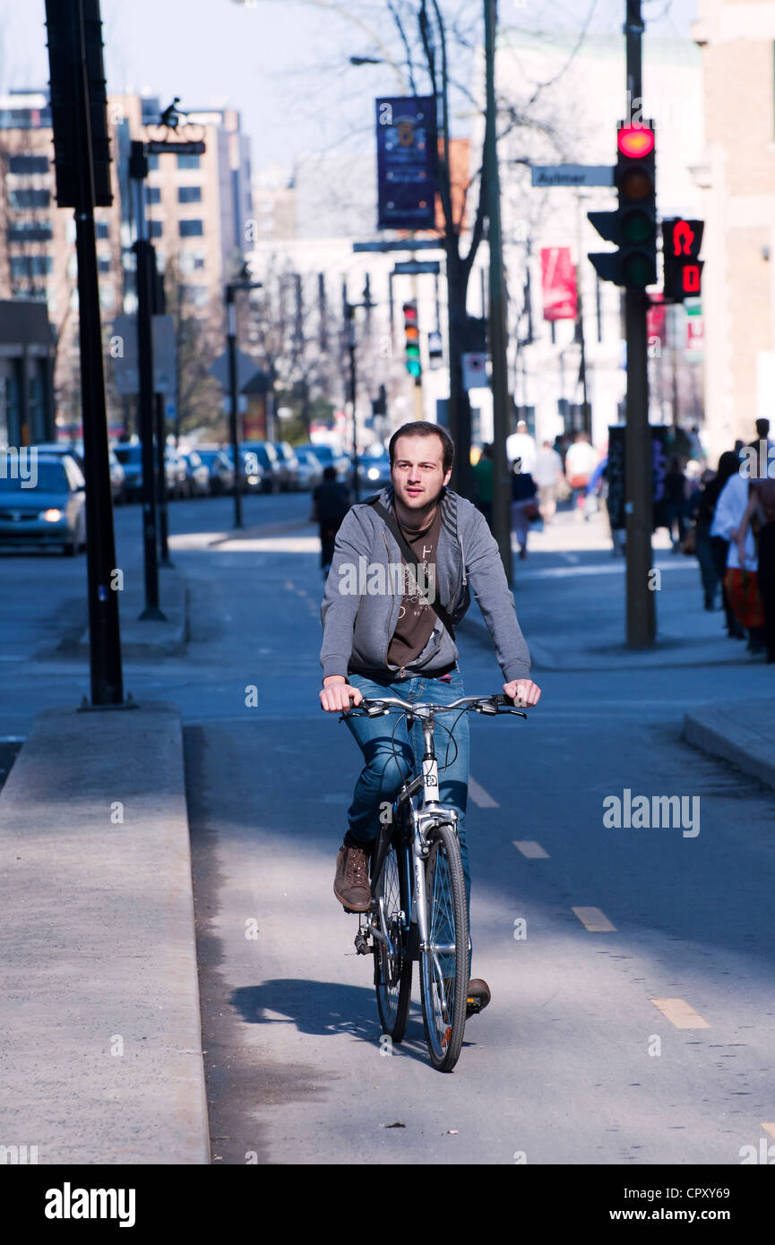 Young man riding a bike on a cycling path in downtown Montreal