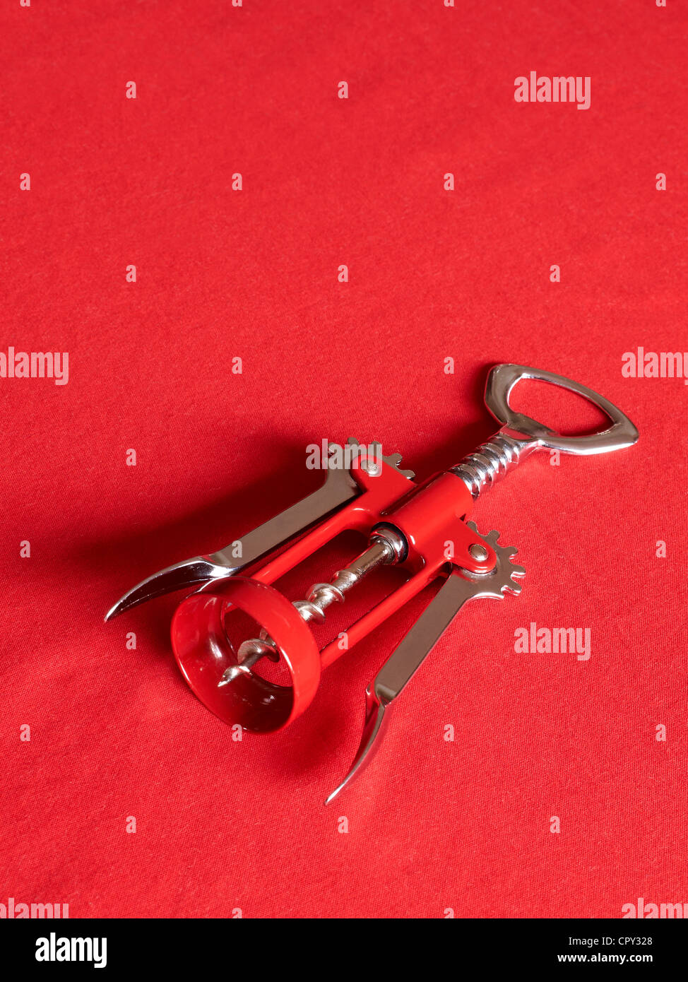 Close up of a corkscrew with bottle opener isolated on red background Stock Photo