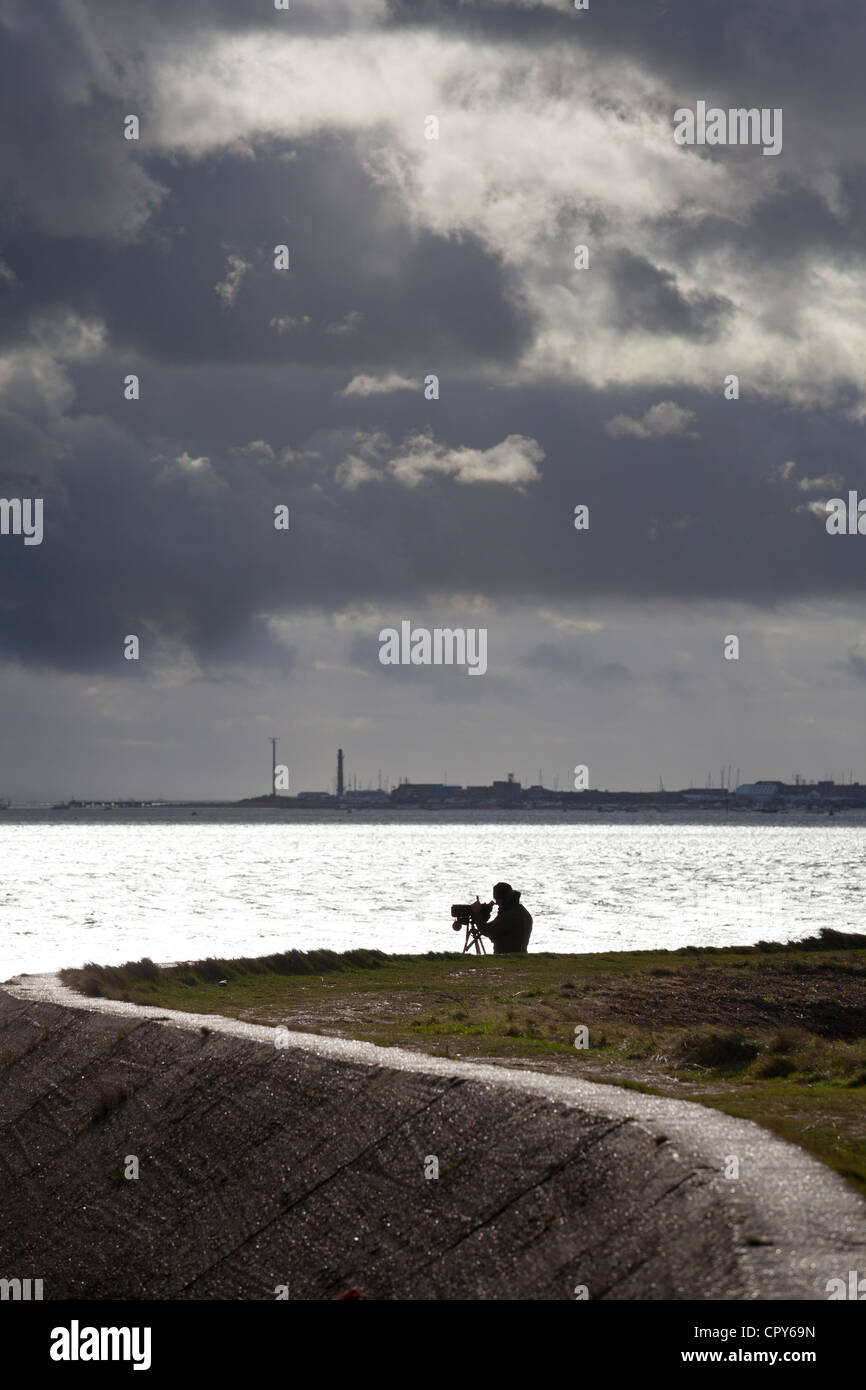 bird watcher at Farlington marshes wetlands by sea wall on stormy day Stock Photo