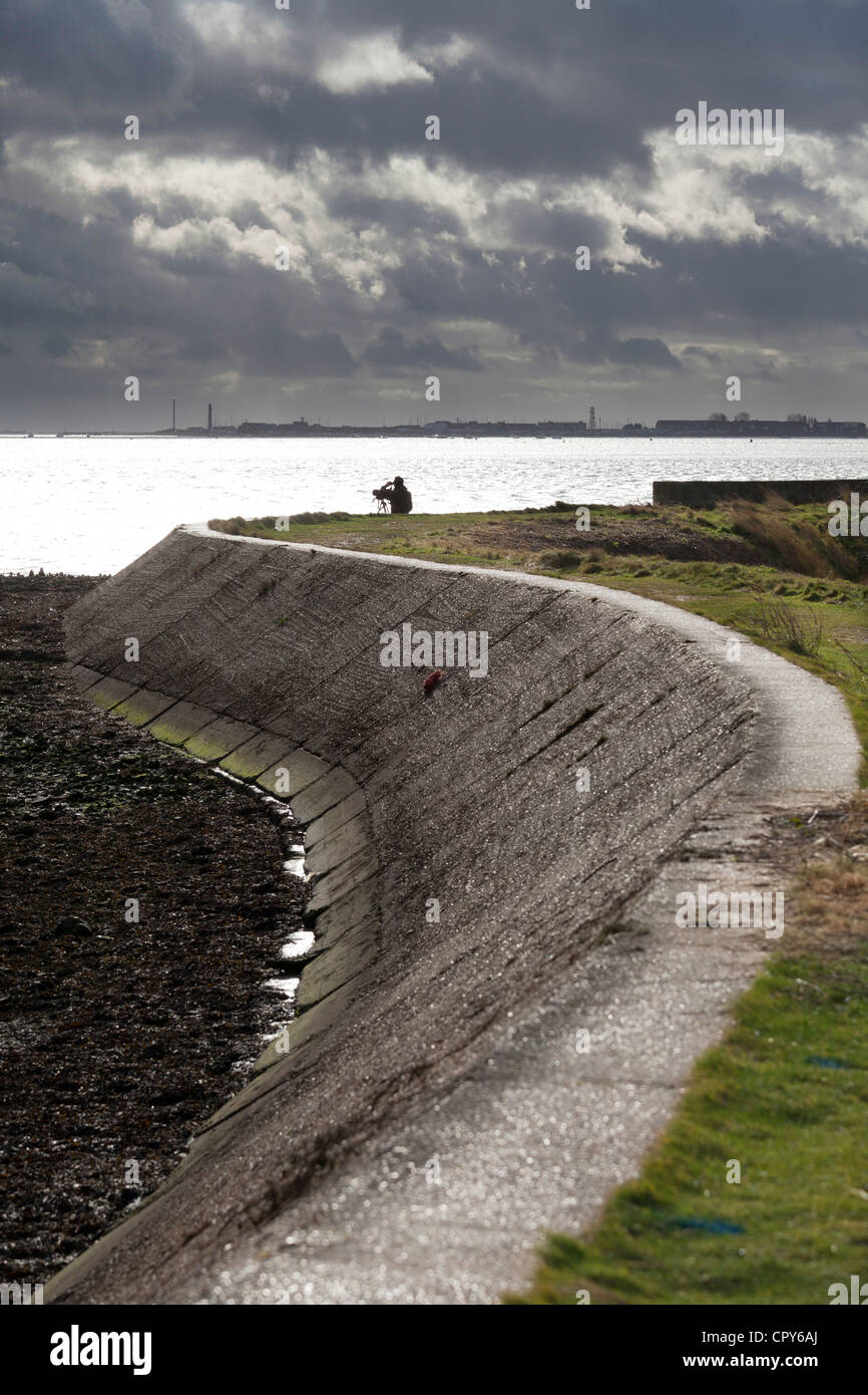 bird watcher at Farlington marshes wetlands by sea wall on stormy day Stock Photo