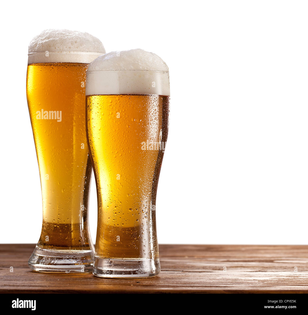 Two glasses of beers on a wooden table. Isolated on a white background. Stock Photo