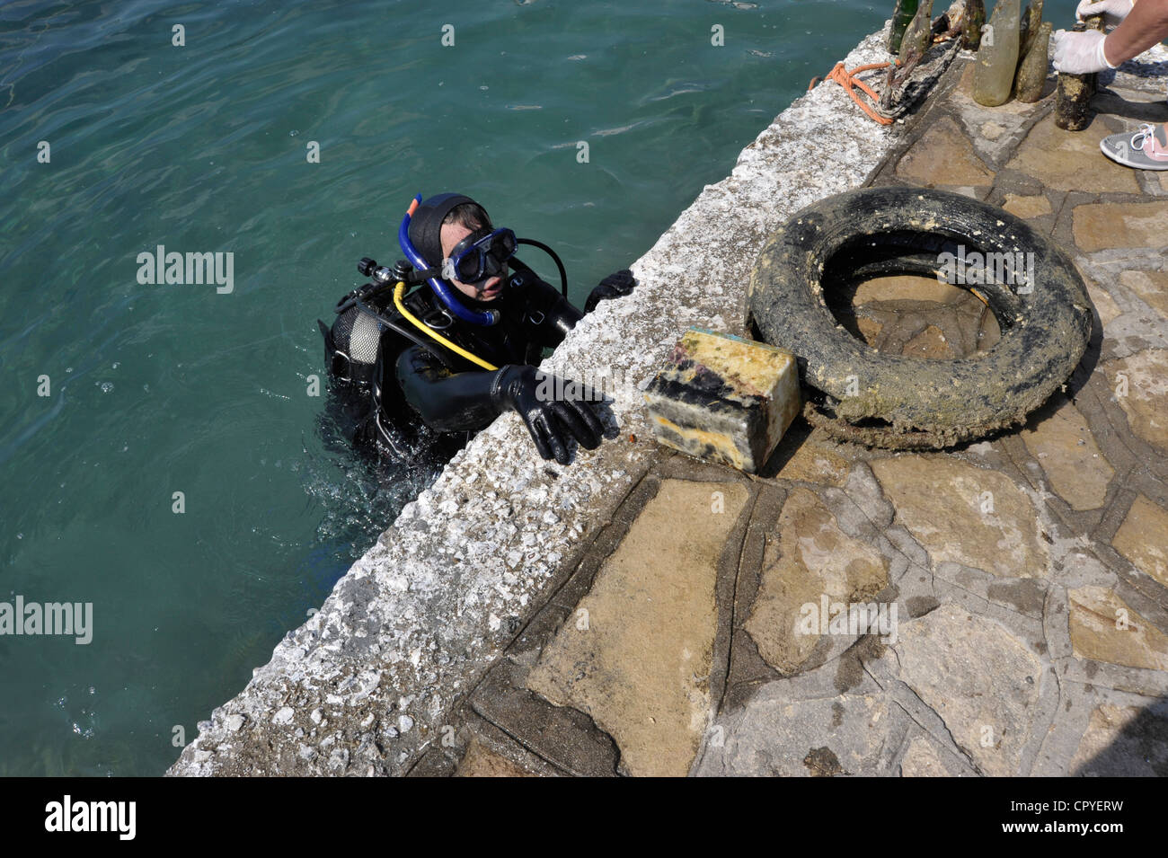 Diver taking old tires and battery out of the sea. Stock Photo