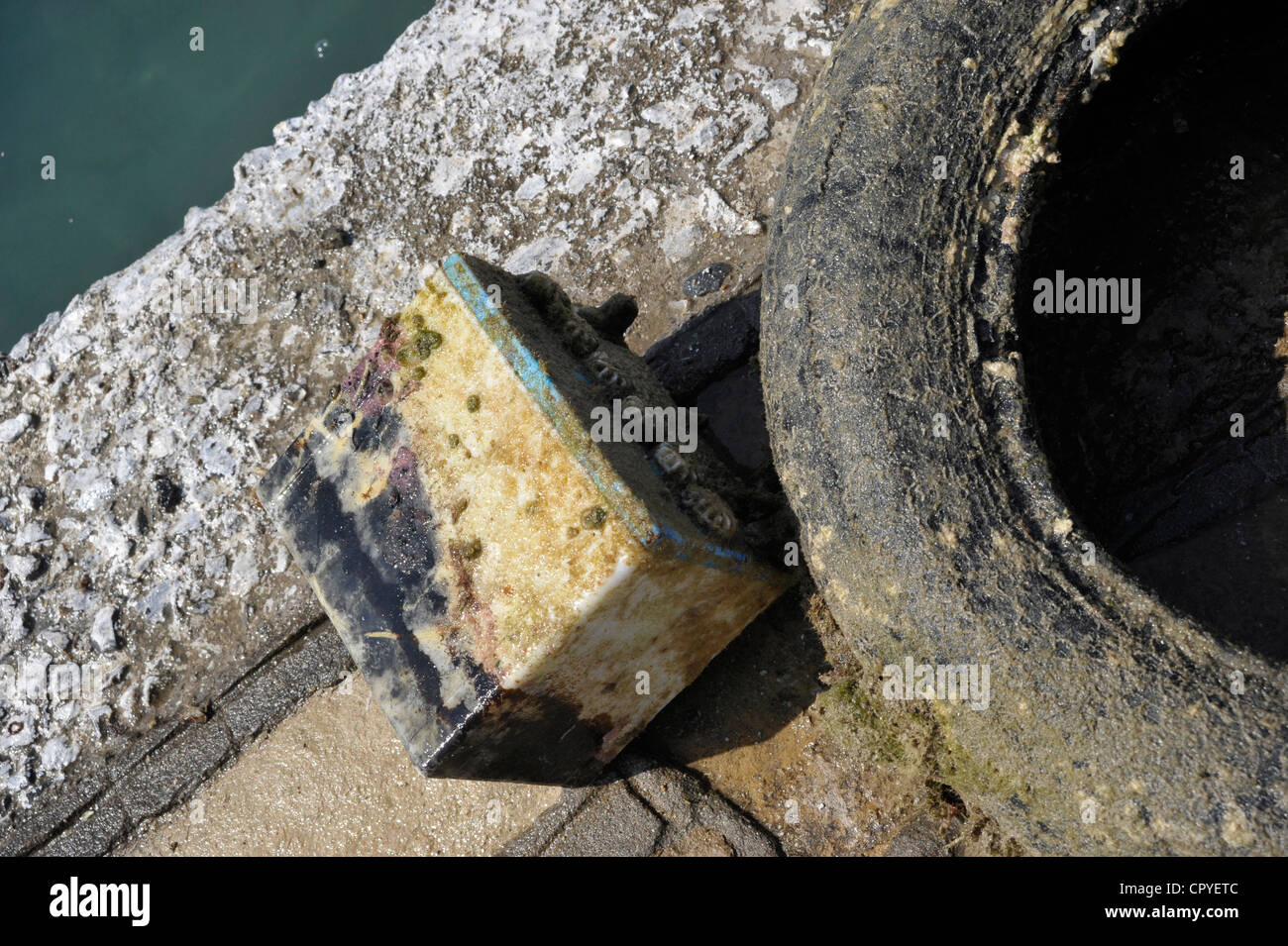 Old tire and battery taken off the sea. Stock Photo