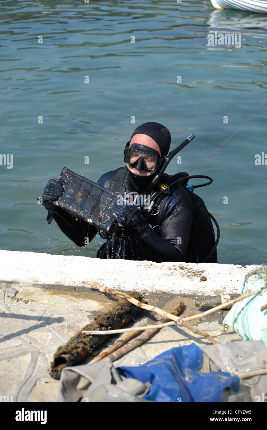 Diver taking old battery off the sea. Stock Photo