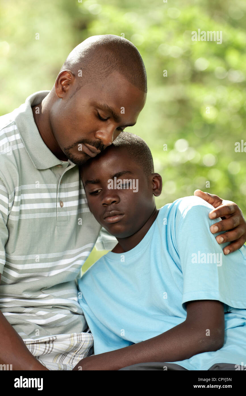 African father and son sitting outside in a garden Stock Photo