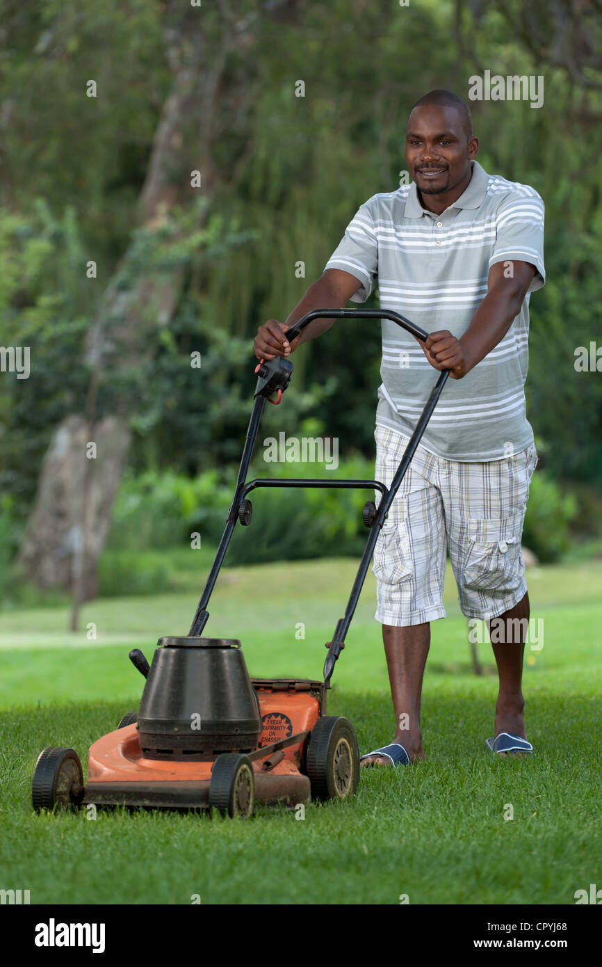 African man mowing the lawn Stock Photo