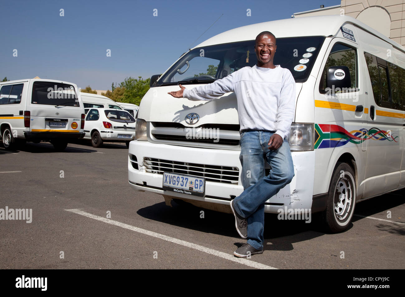 Taxi driver stands in front of his taxi, smiling at camera Stock Photo