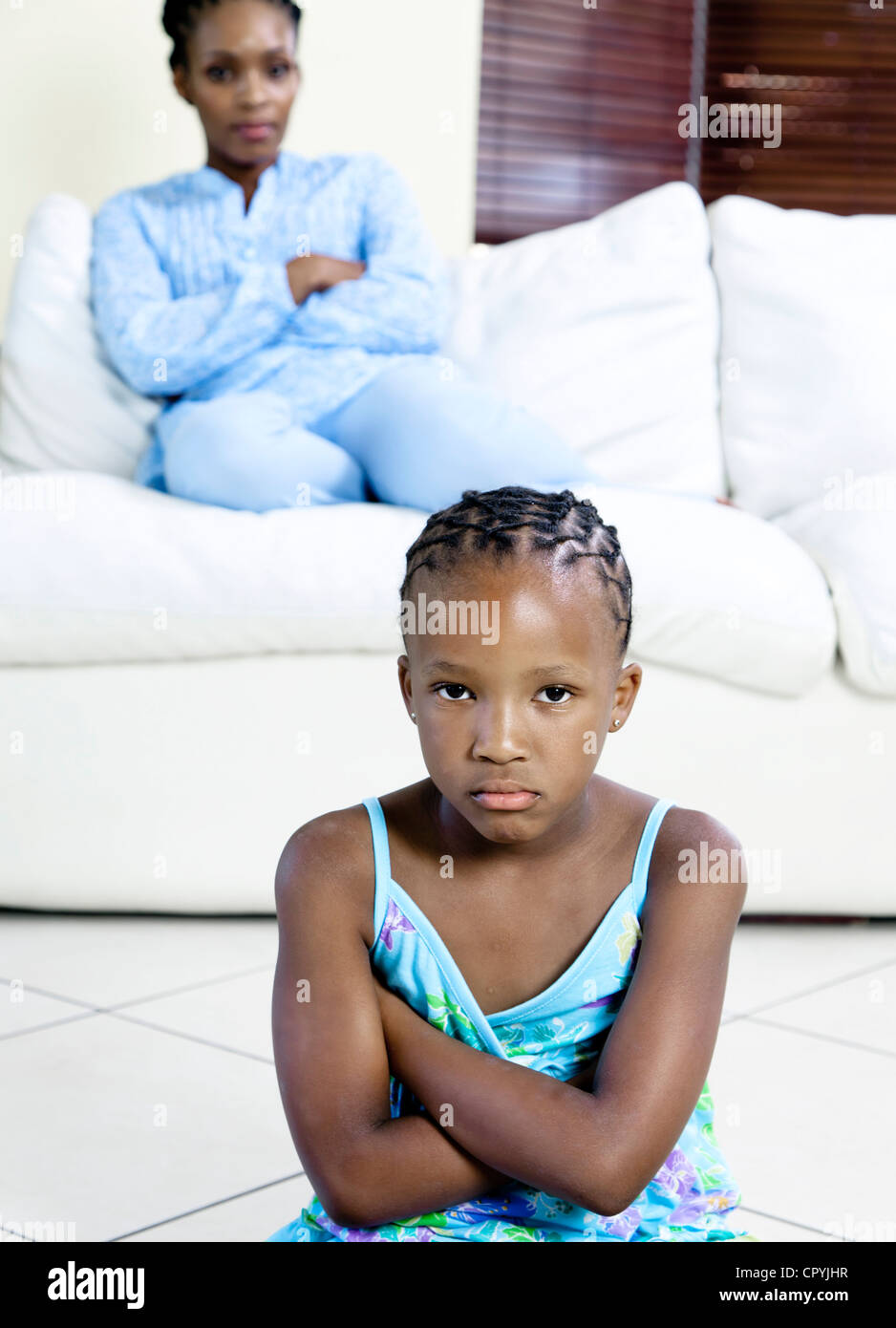 Young African girl frowning with mother in background Stock Photo