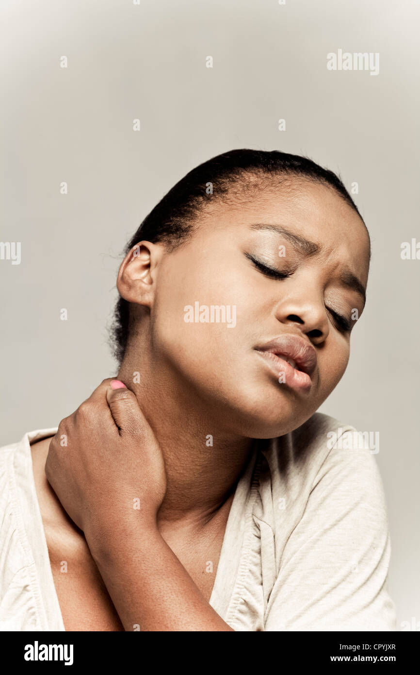 Portrait of young black woman holding her neck in apparent pain Stock