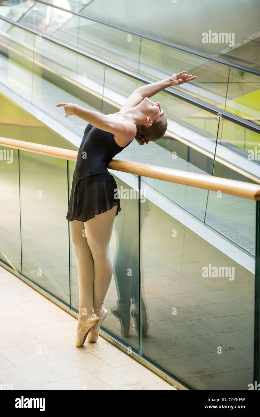 Ballet dancer (ballerina) dancing in modern shopping premises at escalator Stock Photo