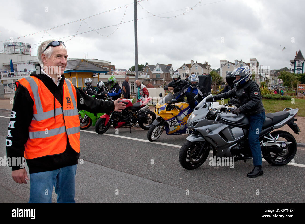 Devon,UK. A marshal at a Paignton Bike Night charity fund raising event  directs motorcycles to the parking area on the seafront Stock Photo - Alamy