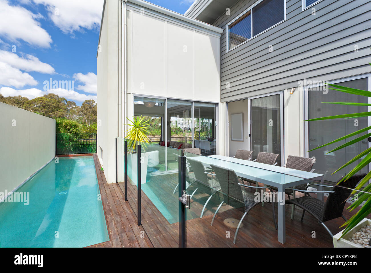 Modern backyard with outdoor table chairs and swimming pool Stock Photo