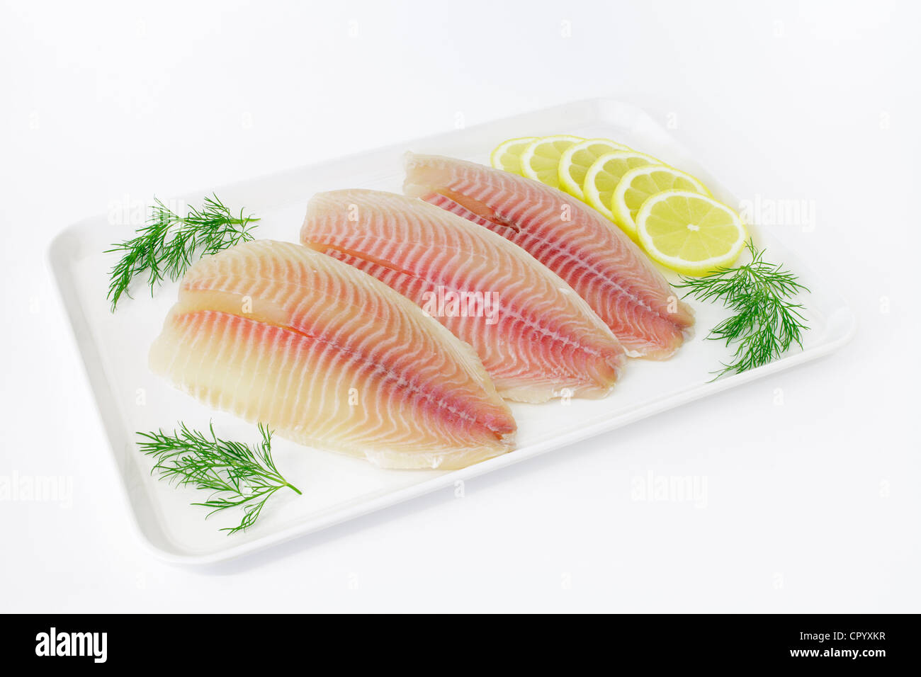 Tilapia fillets on a plate with lemon and dill Stock Photo