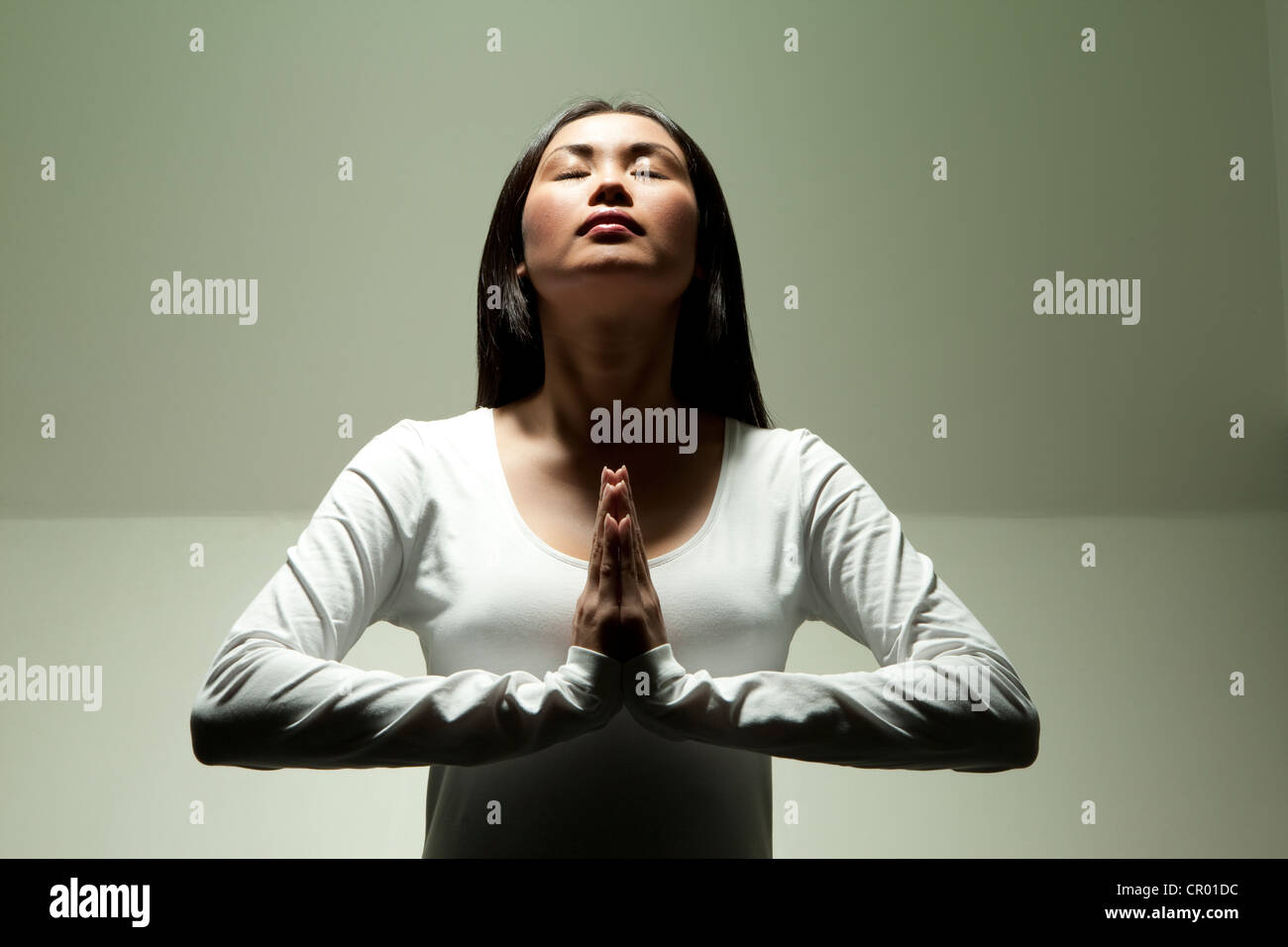 Woman meditating under spotlight Stock Photo