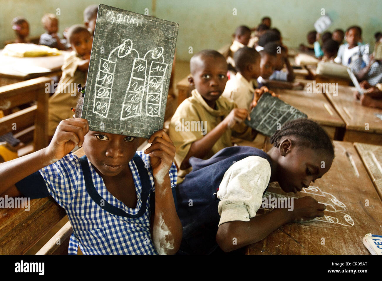 A girl holds up her slate to show the solution she's found to a math problem during class at the groupe scolaire Bondoukou Est Stock Photo