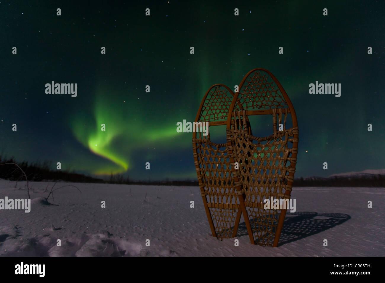Traditional wooden snow shoes, against swirling Northern lights, Polar aurora or Aurora Borealis, green, near Whitehorse Stock Photo