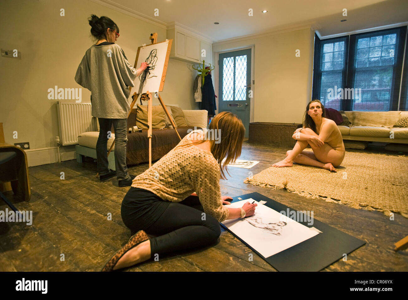 Women in an art class drawing a nude female model Stock Photo