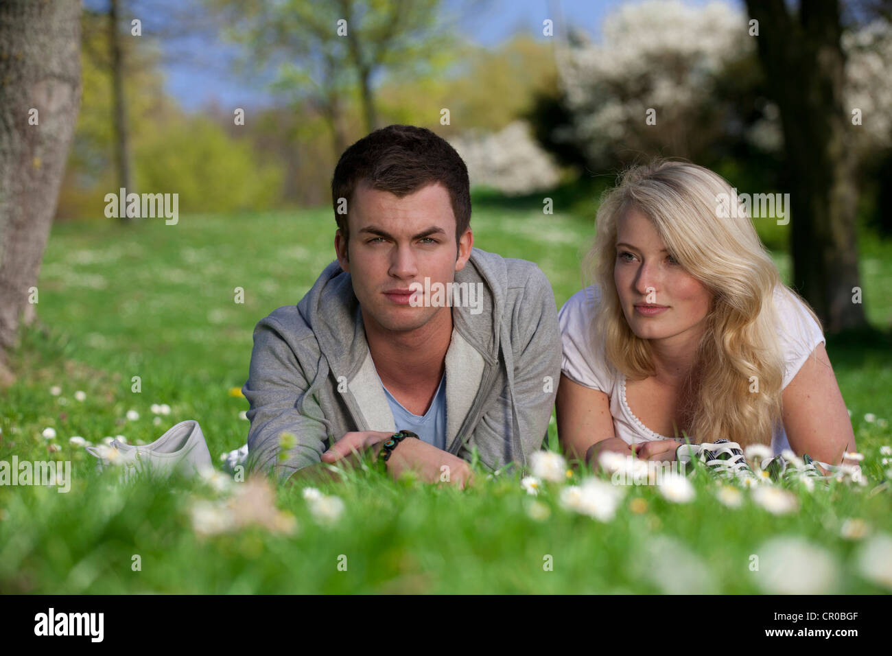 Young couple lying on a lawn in a park, spring Stock Photo