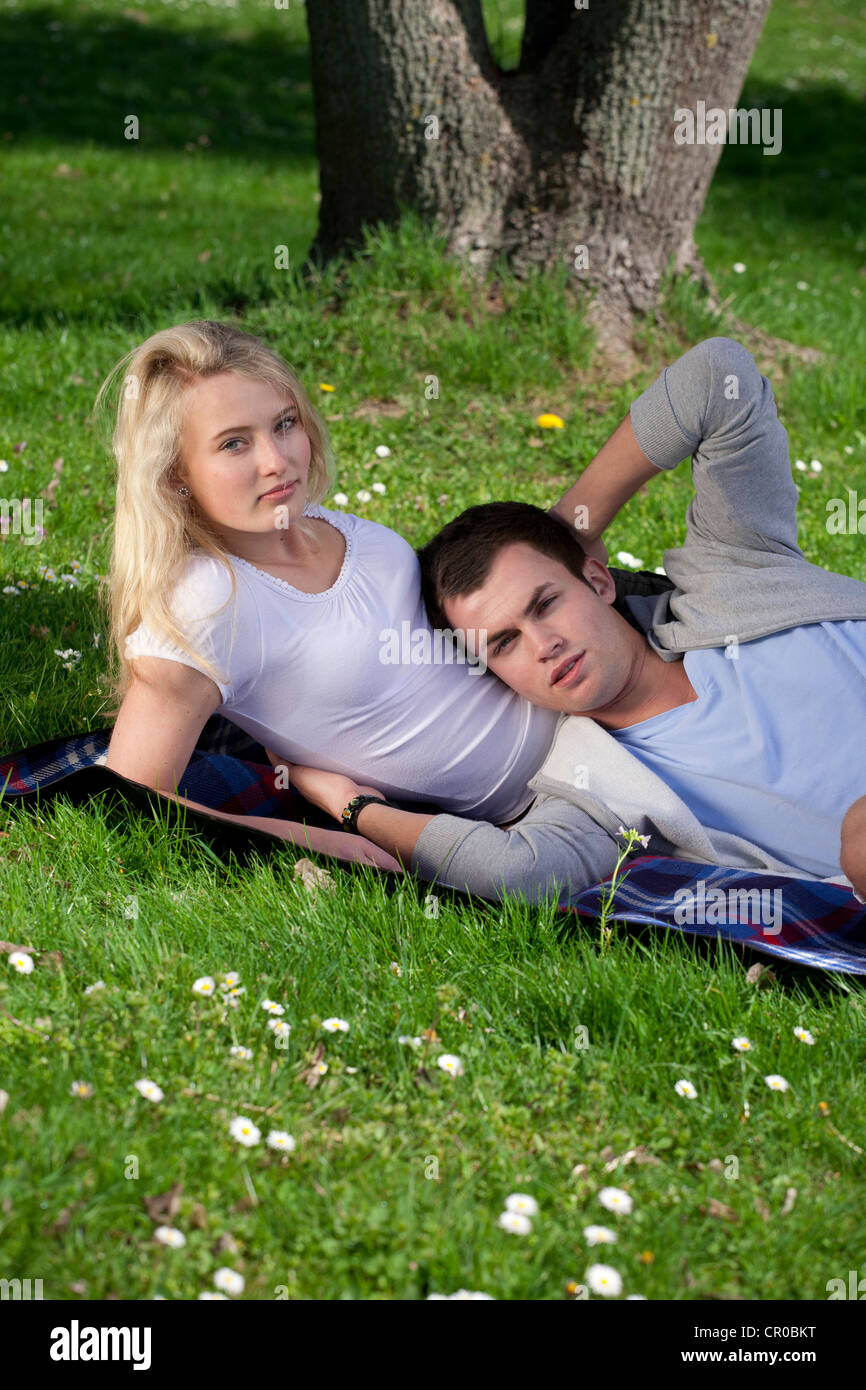 Young couple lying on a lawn in a park, spring Stock Photo