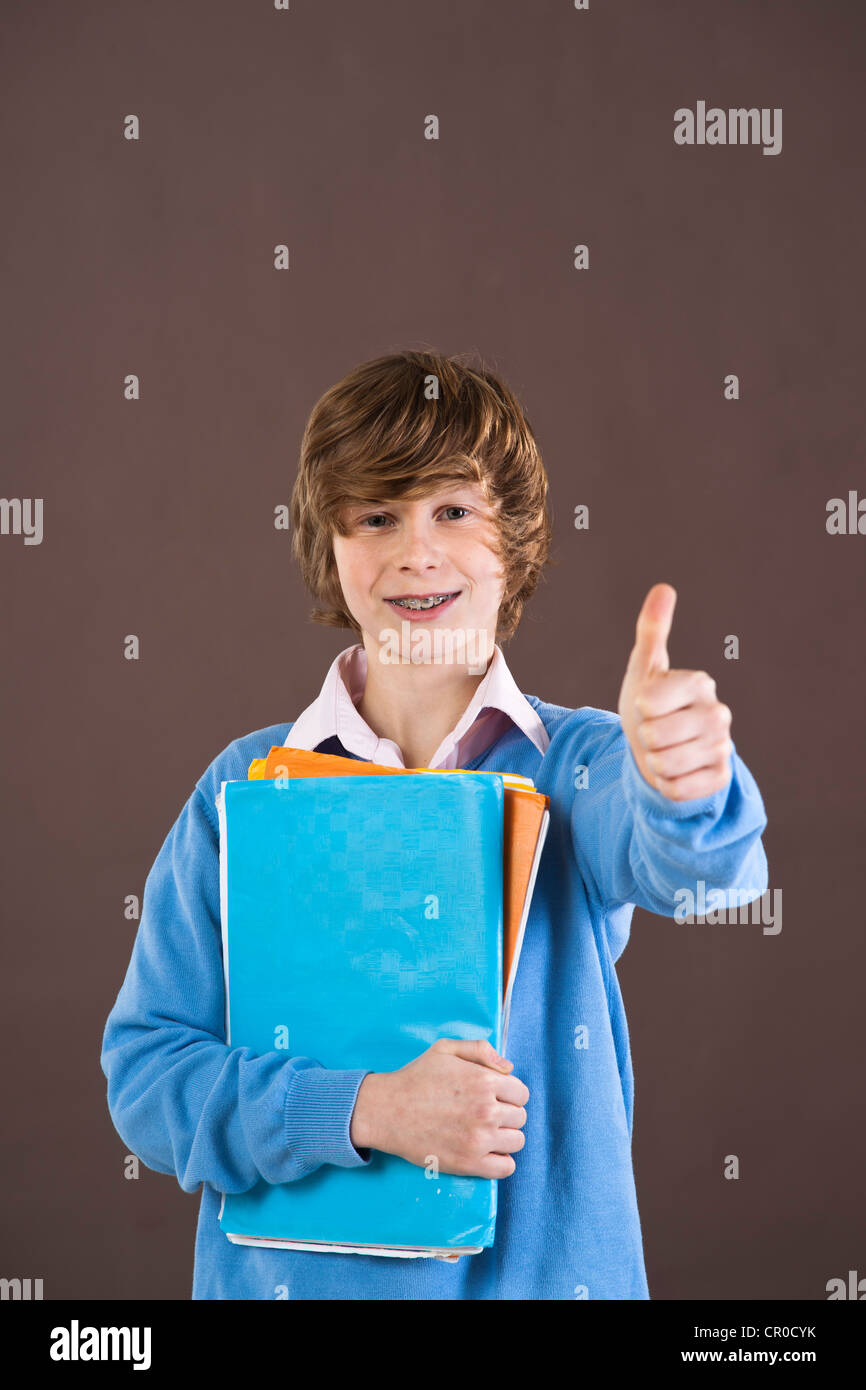 Boy holding school books making a thumbs-up gesture Stock Photo