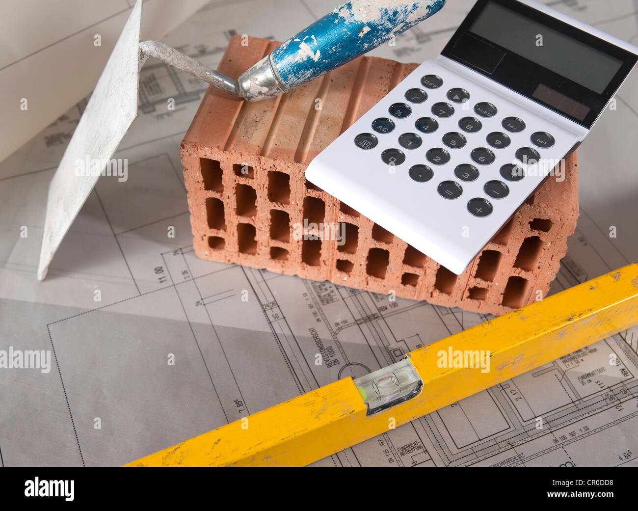 Calculator, spirit level, trowel and a brick on a building plan Stock