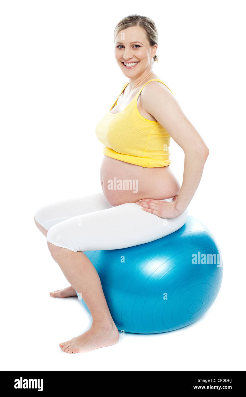 Pregnant woman exercises with big blue gymnastic ball. Smiling and