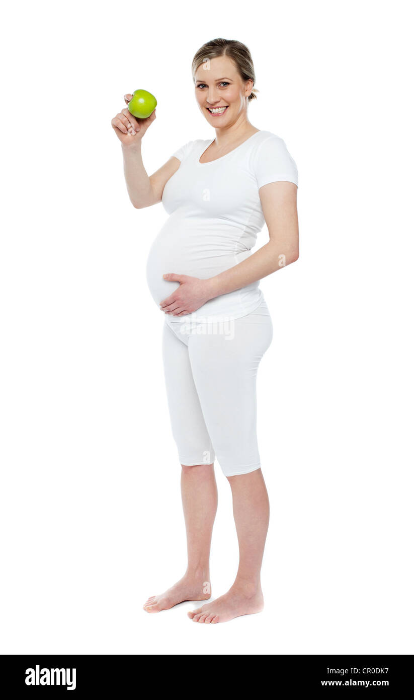 Pregnant woman showing fresh green apple while holding her belly