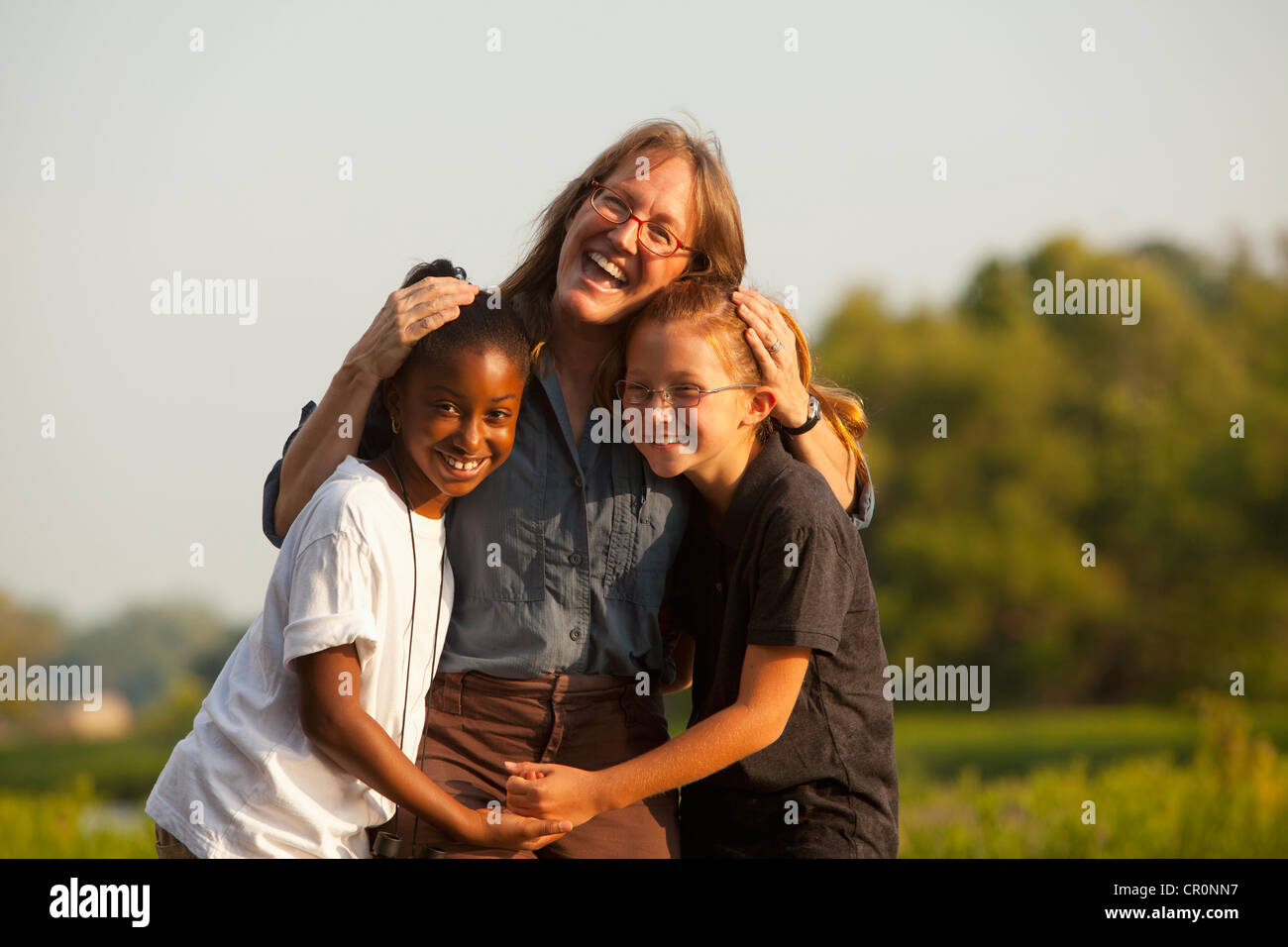 Teacher hugging students outdoors Stock Photo