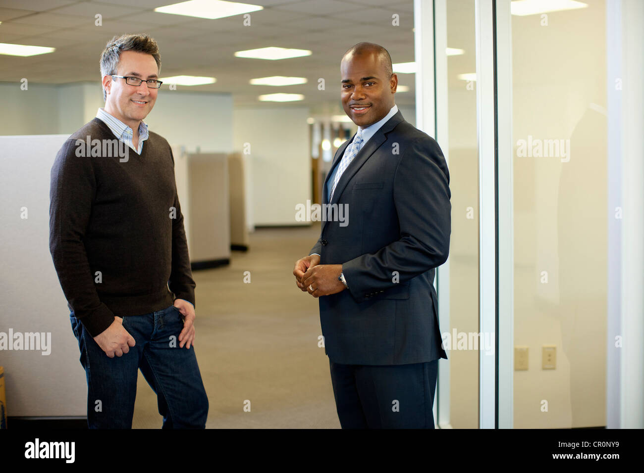 Smiling businessmen standing together in office Stock Photo - Alamy