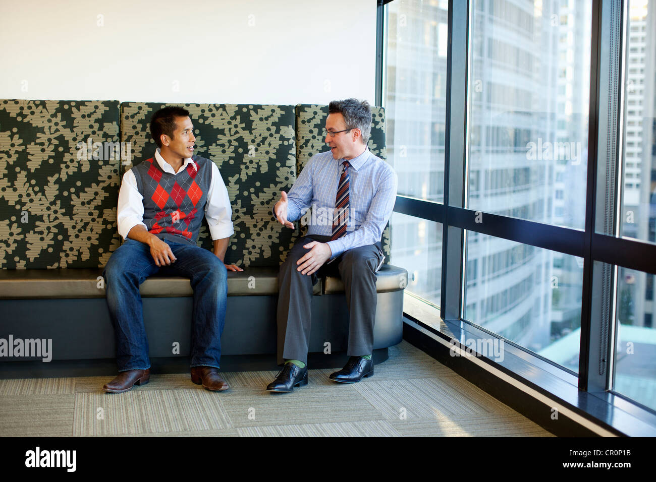 Businessmen talking together in office lobby Stock Photo - Alamy