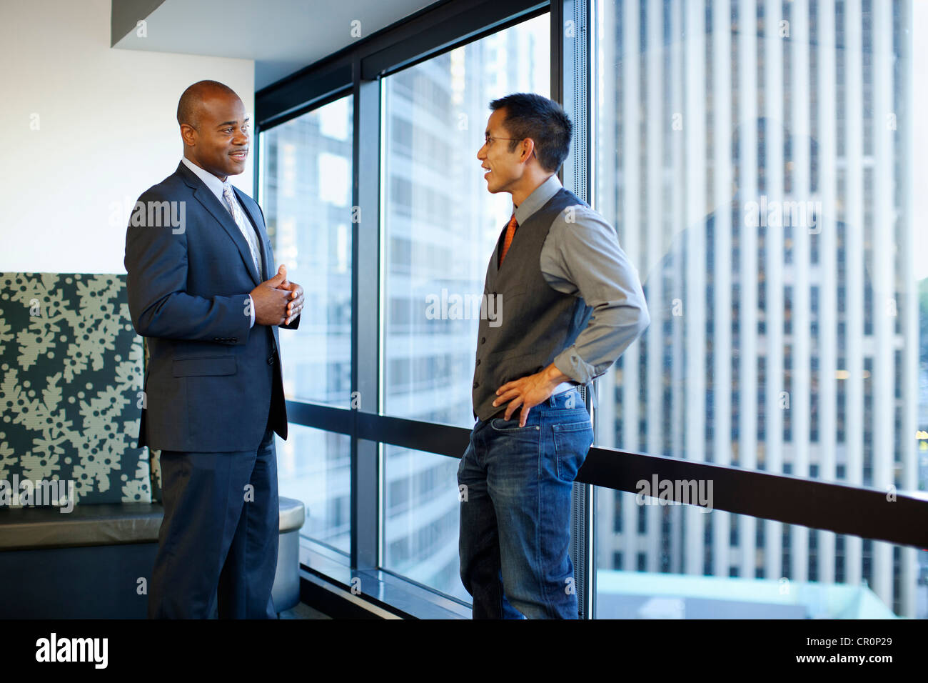 Businessmen talking together in office lobby Stock Photo - Alamy
