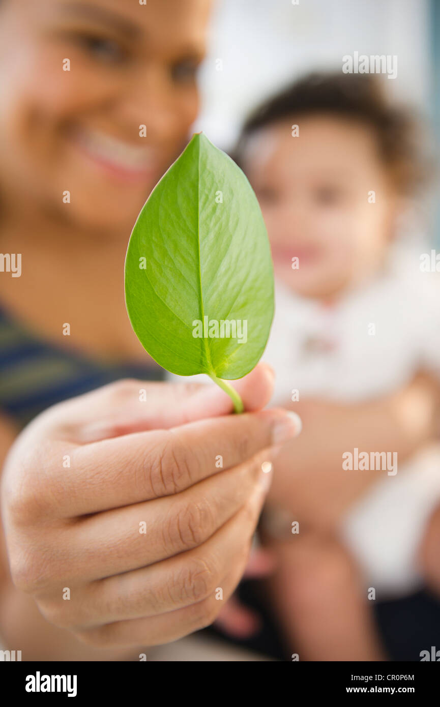 Mixed race woman holding baby and green leaf Stock Photo