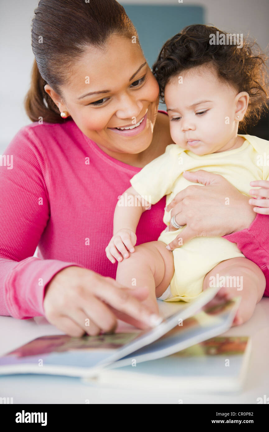 Mixed race mother reading book to baby Stock Photo