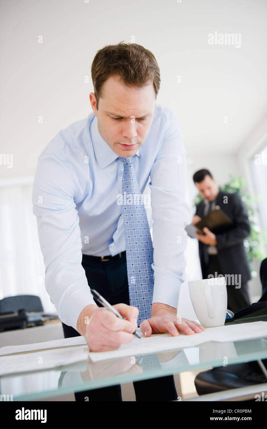 Caucasian businessman leaning on desk and writing Stock Photo