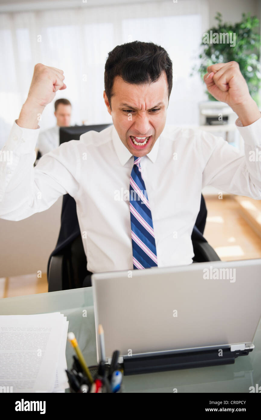 Angry mixed race businessman shouting in laptop Stock Photo