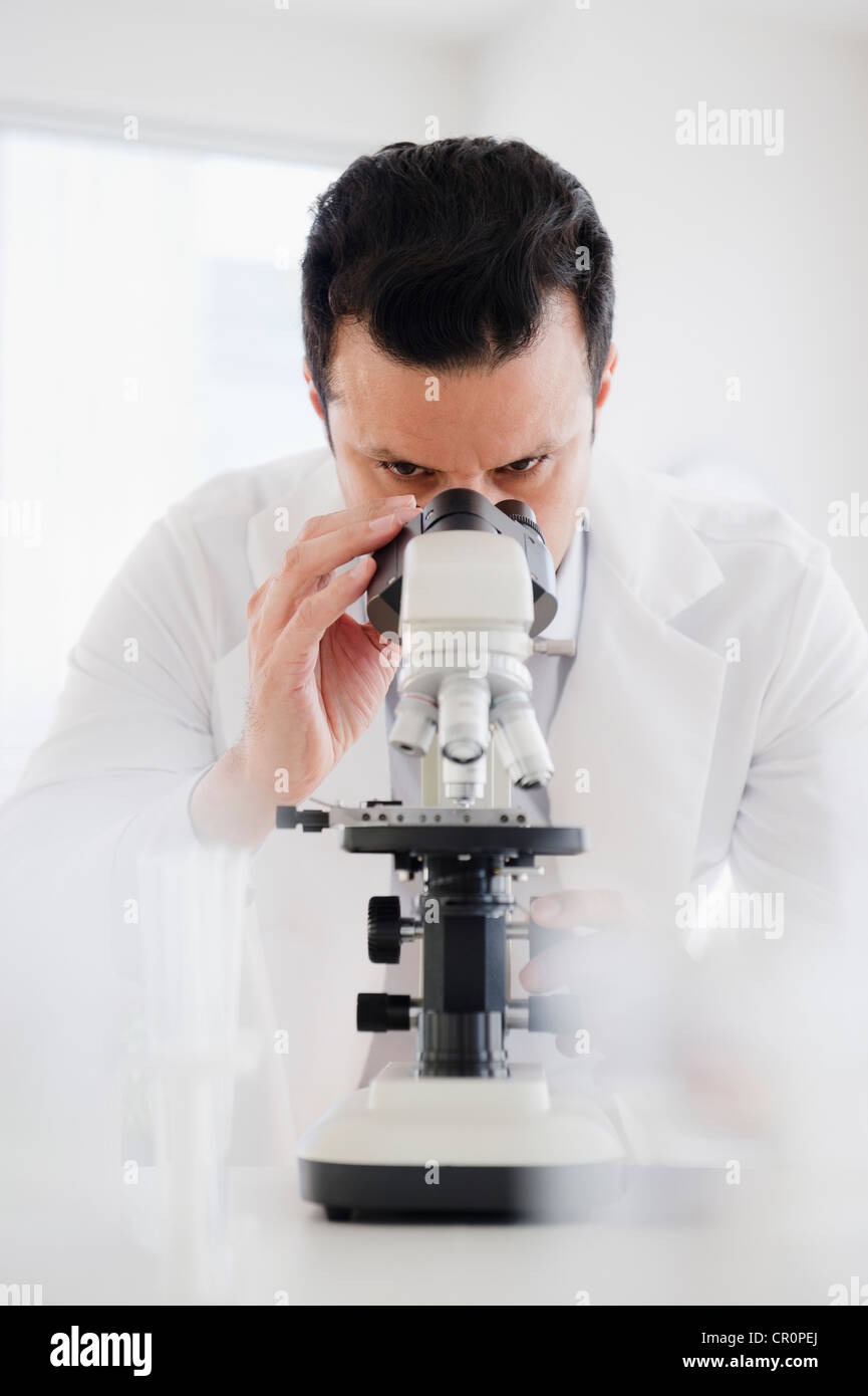 Mixed race scientist looking into microscope Stock Photo