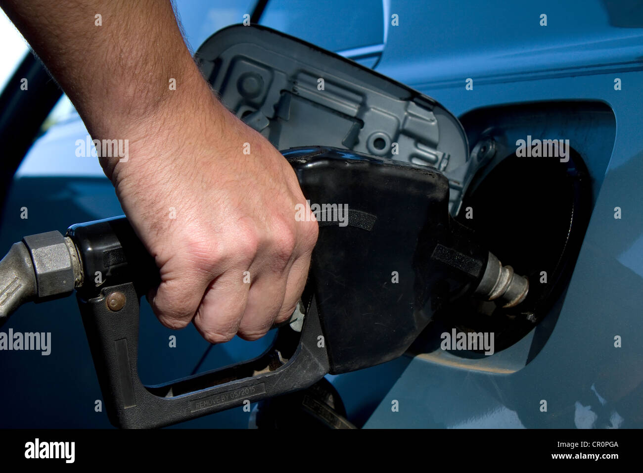 Close up of man hand holding gas pump handle and filling the fuel tank on his vehicle. Stock Photo