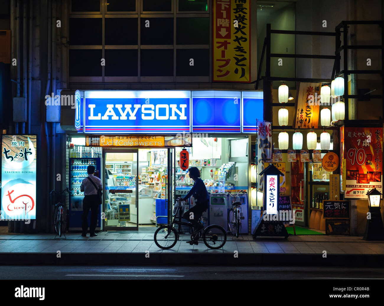 Lawson convenience store at night with cyclist. Japan. Stock Photo