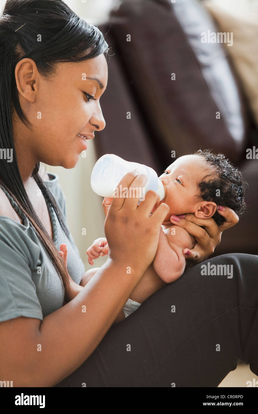 Mixed race mother feeding bottle to newborn baby Stock Photo Alamy