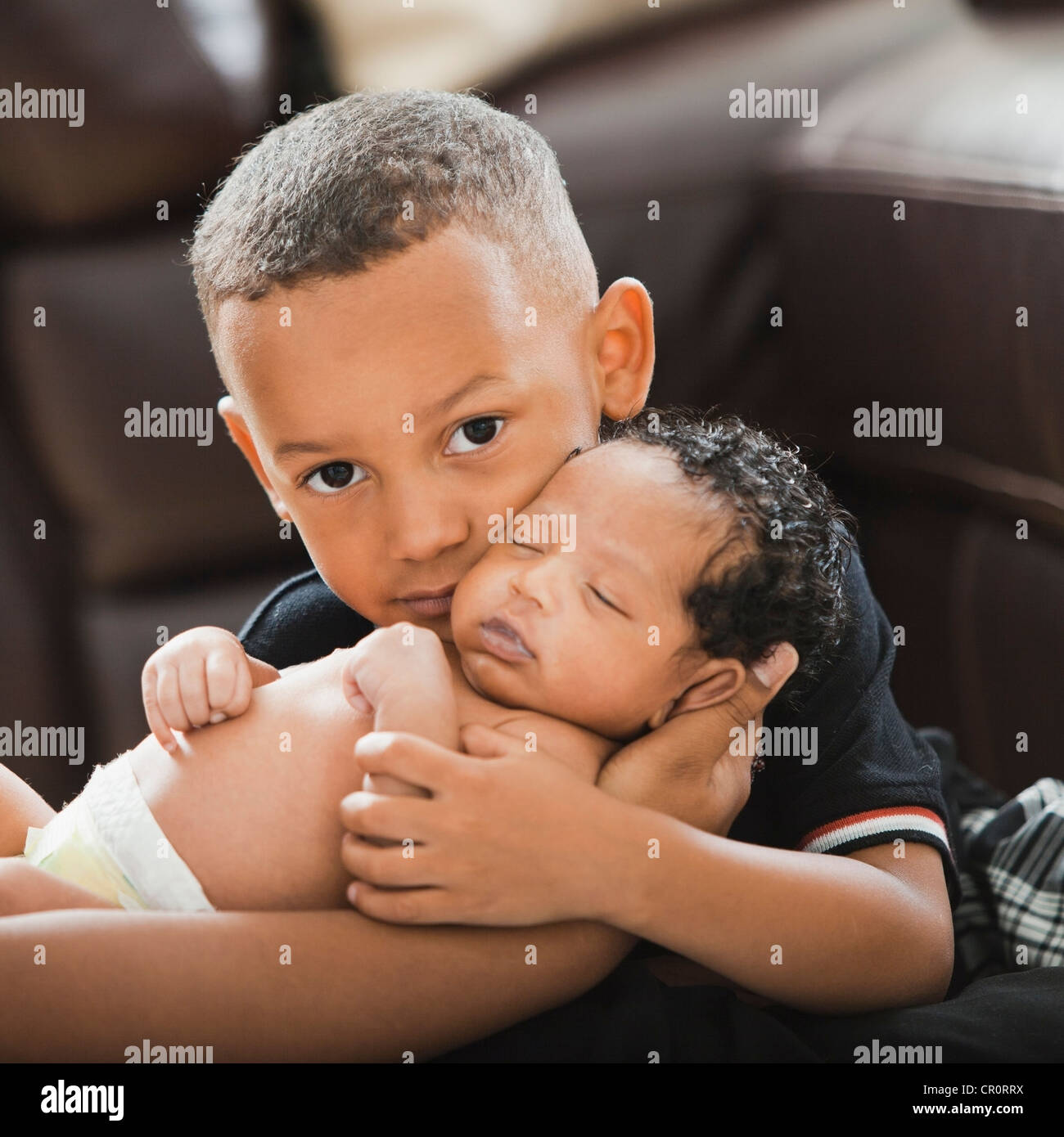 Mixed race boy hugging newborn baby Stock Photo - Alamy