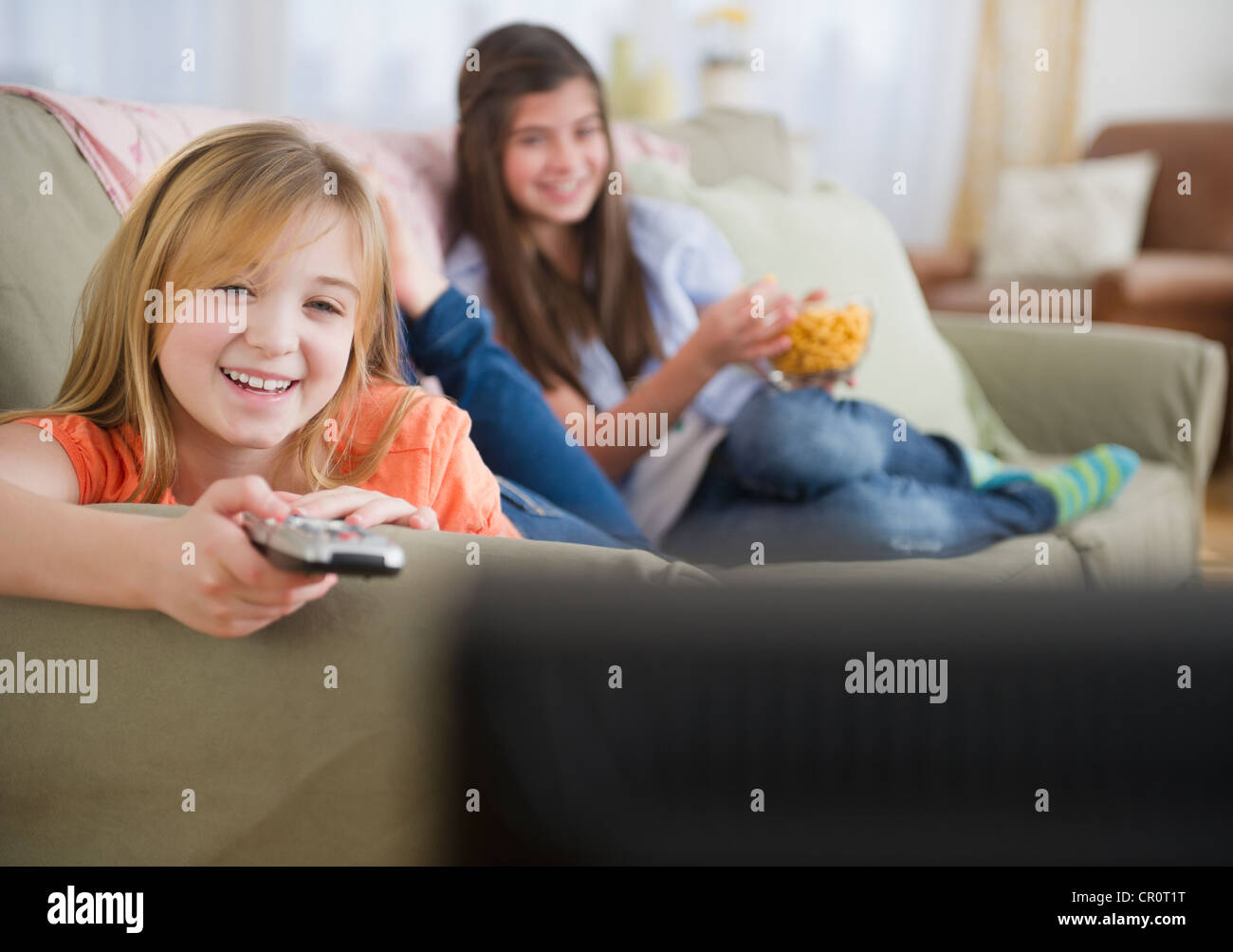 USA, New Jersey, Jersey City, Two girls watching tv on sofa Stock Photo