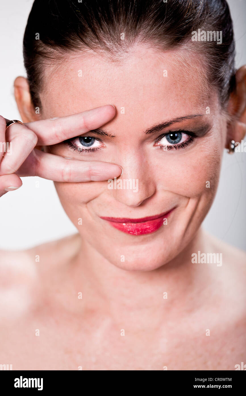 Portrait of a young woman looking cheekily through her fingers Stock Photo
