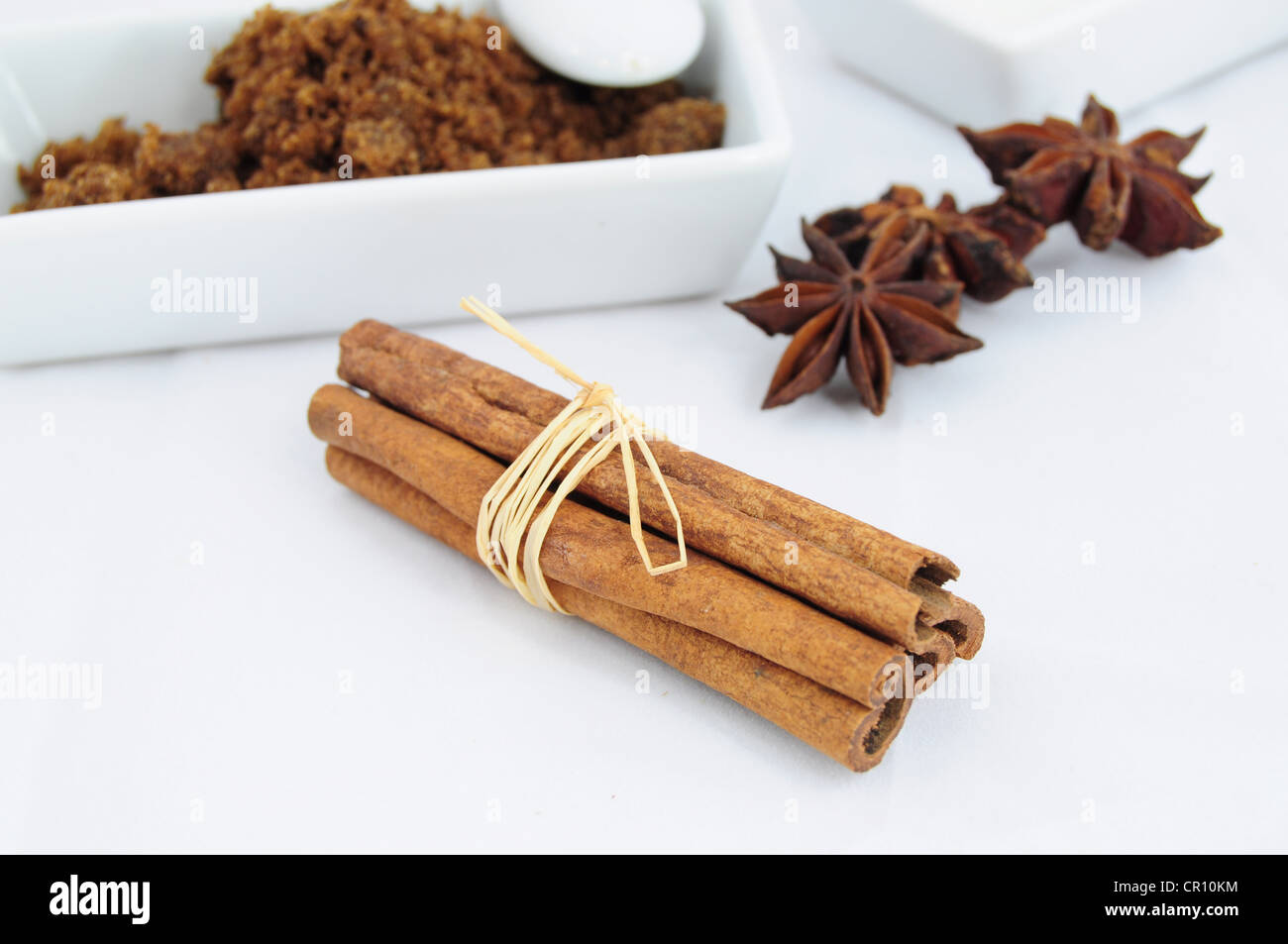 Cinnamon sticks, anise and bowl brown sugar in the background Stock Photo