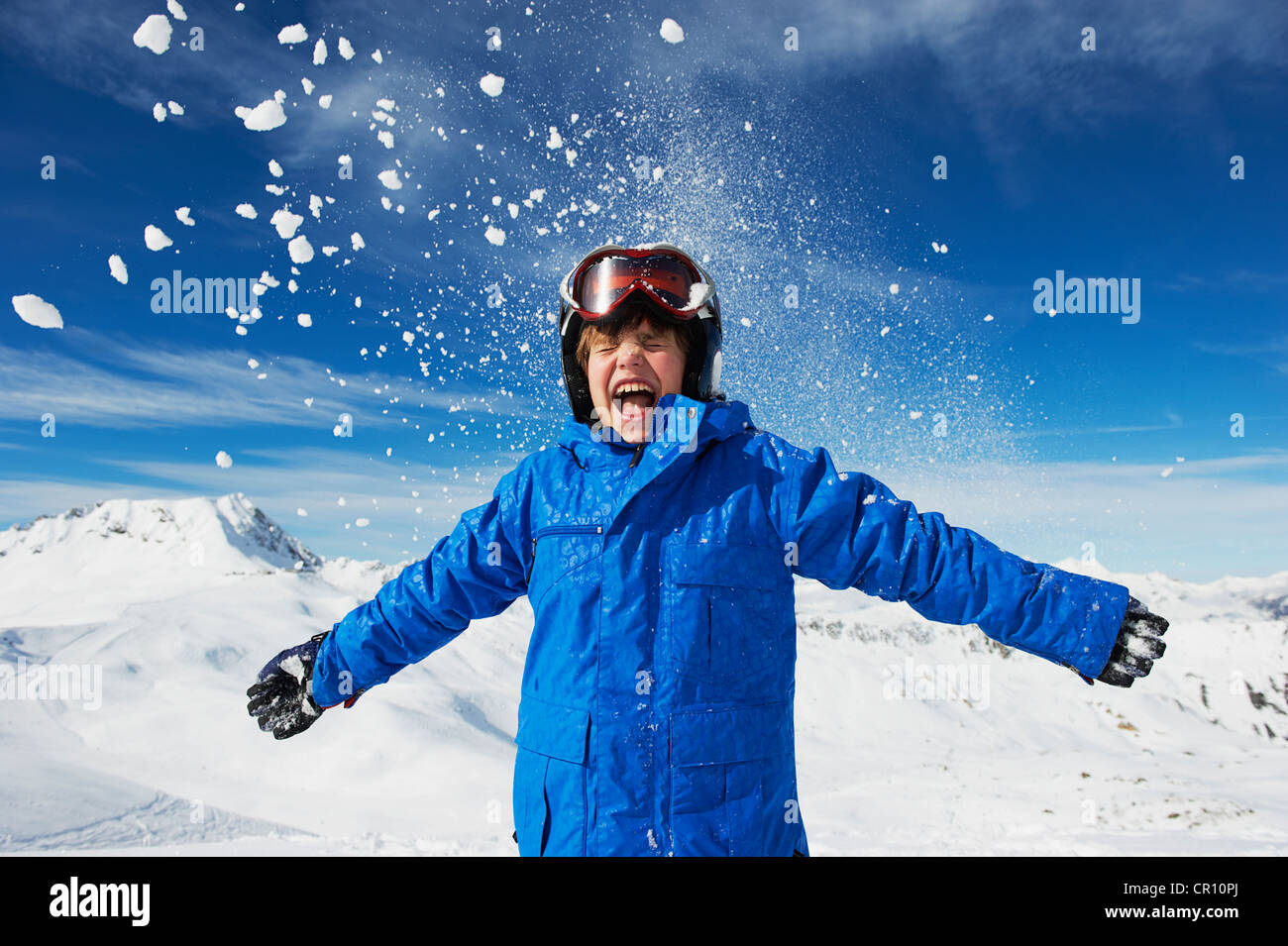 Boy cheering on snowy mountaintop Stock Photo